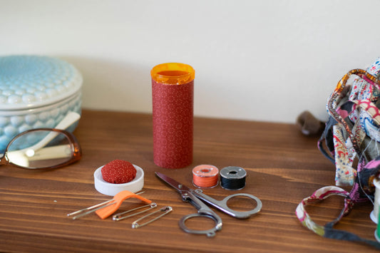 upcycled prescription bottle sewing kit — pink circular small dots on red, open with contents, 3.25" high