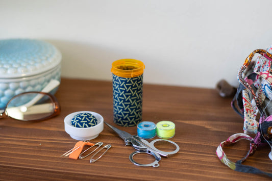 upcycled prescription bottle sewing kit — green sticks on dark blue, 3" high, open with contents